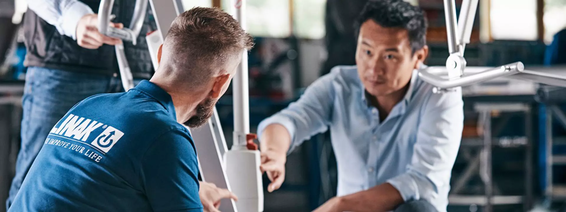 Two people examining components on a LINAK LIFT solution in a workshop setting.