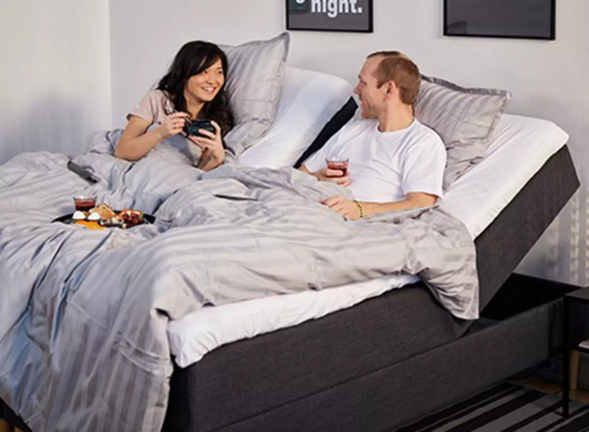 Smiling couple enjoying breakfast in their adjustable comfort bed