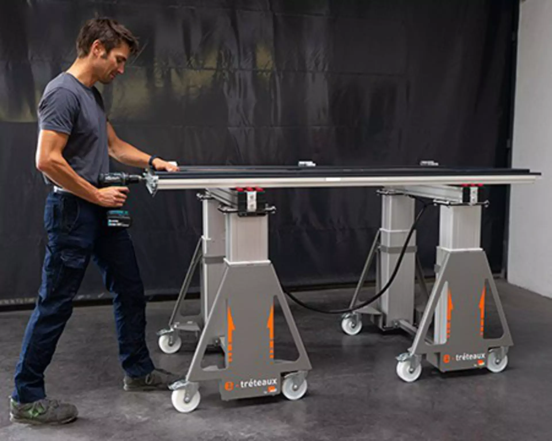 Man working at an electric work trestle, the e-tréteaux, featuring 4 LINAK® DL2 lifting columns.