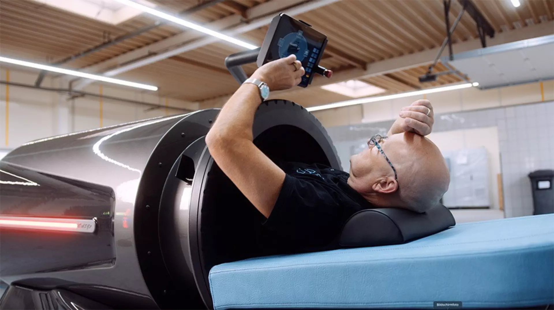Flow system capsule where man lies to his chest looking at a screen. Blue head rest.