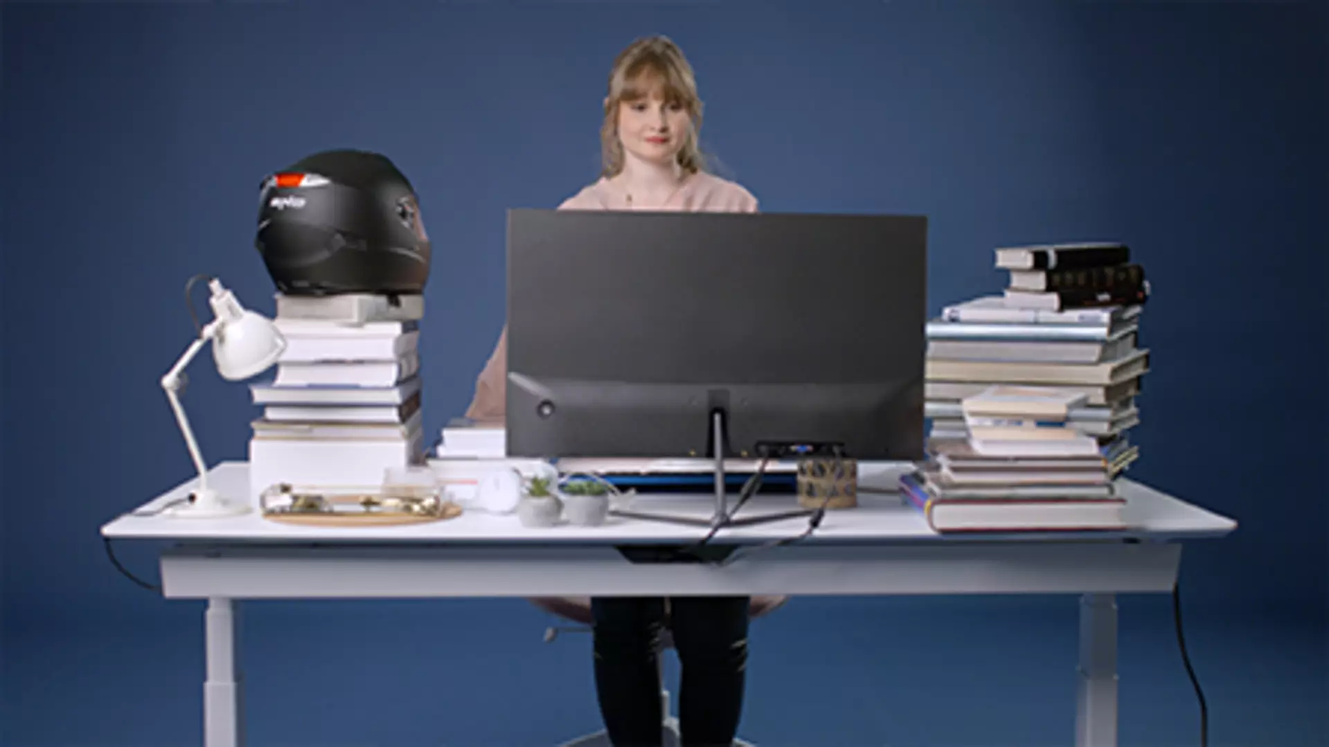 Woman standing at fully loaded height-adjustable desk powered by LINAK system