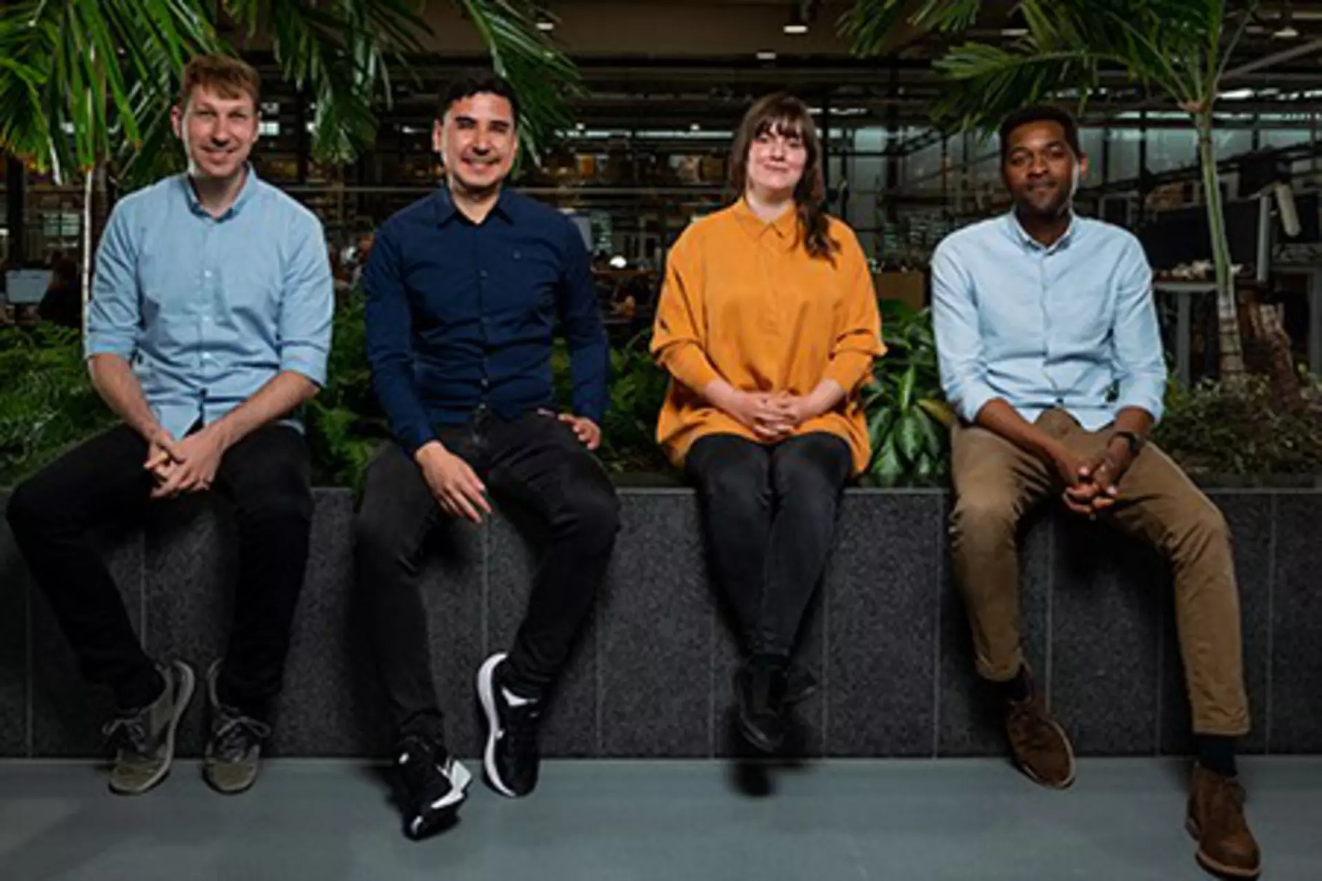 Four LINAK employees sitting in front of the production area.
