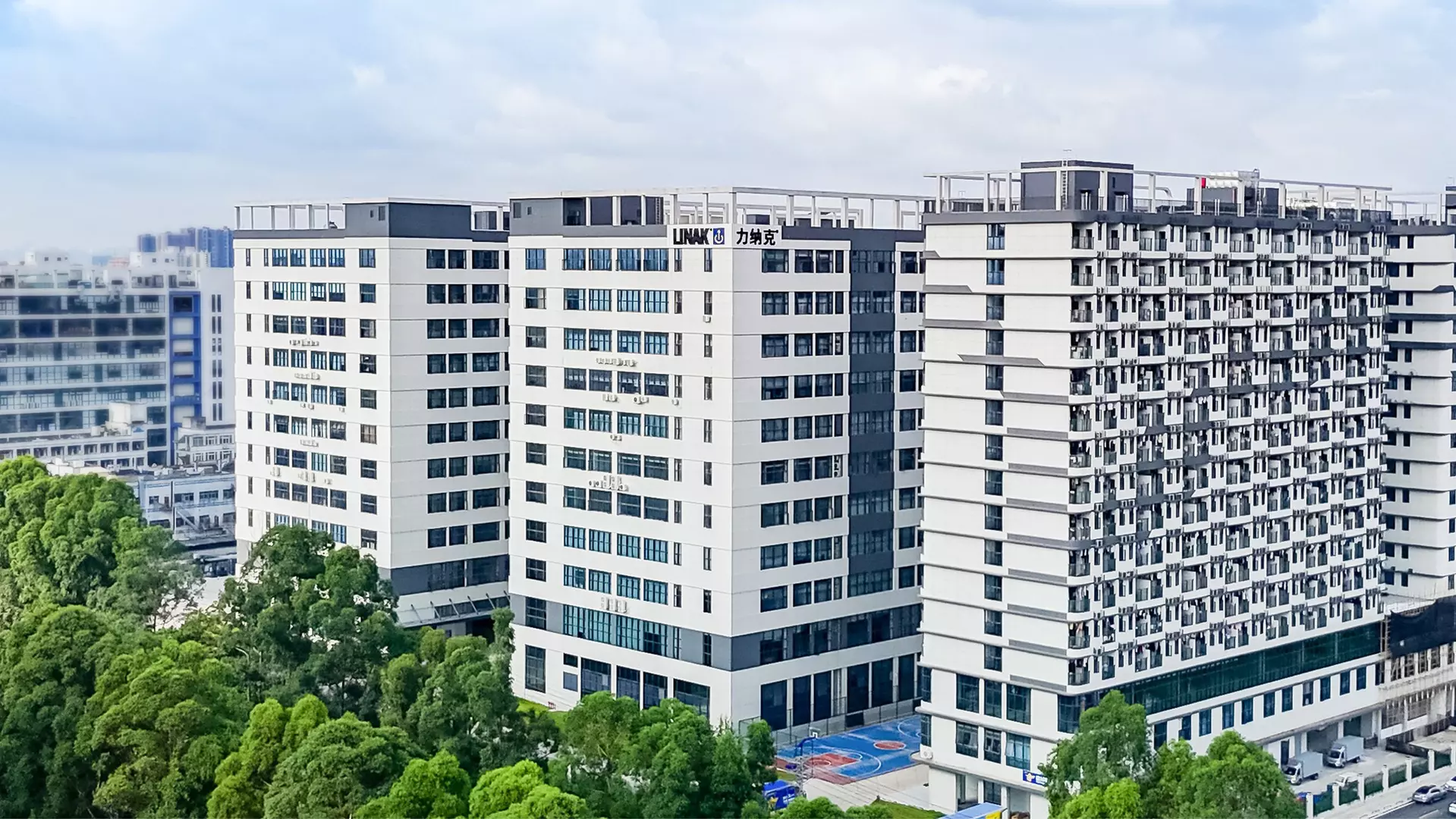 LINAK China - modern office building with multiple floors, glass windows, and surrounding trees viewed from street level.