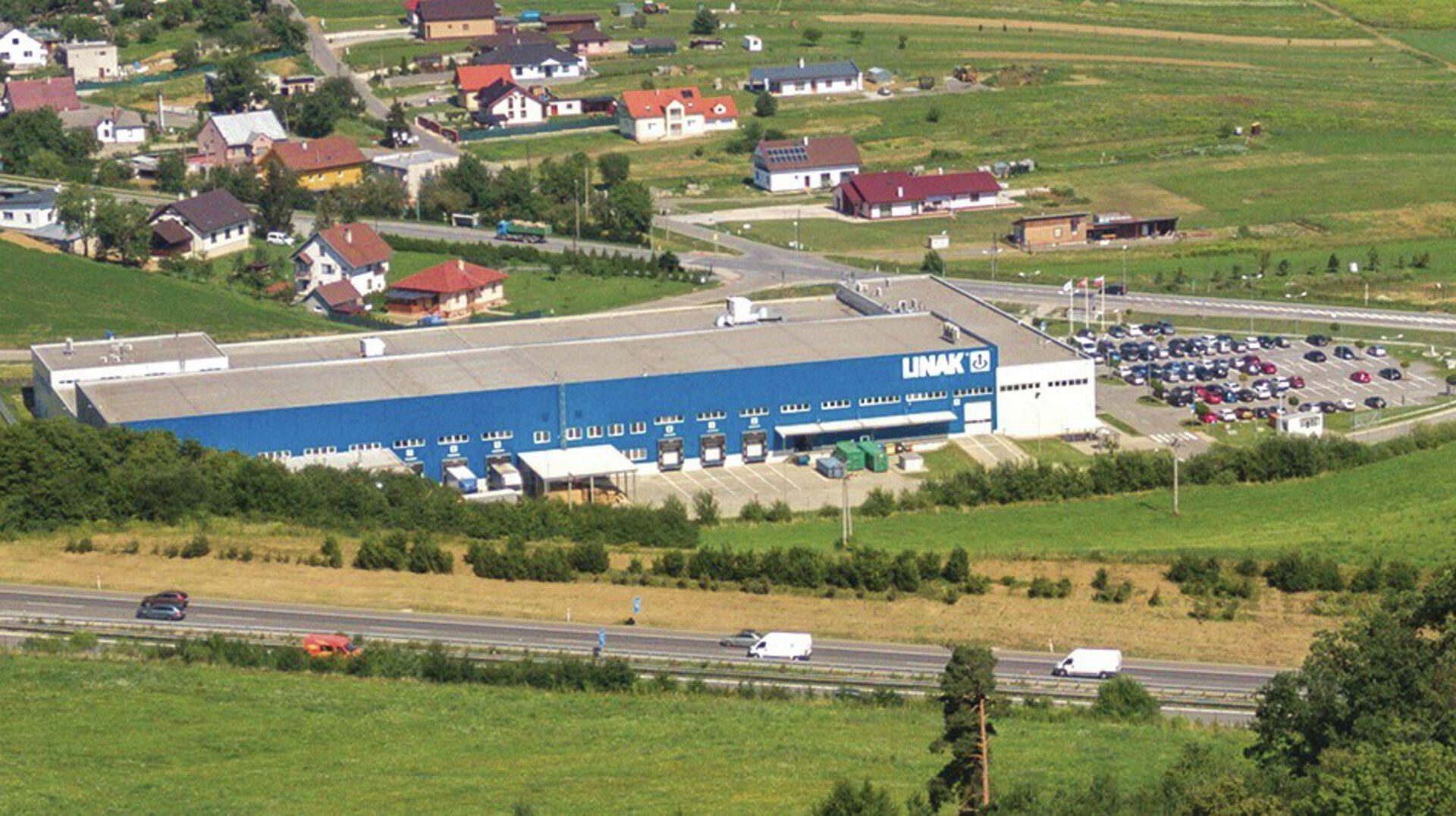 LINAK Slovakia - aerial view of a manufacturing site with large warehouse building and parking areas.